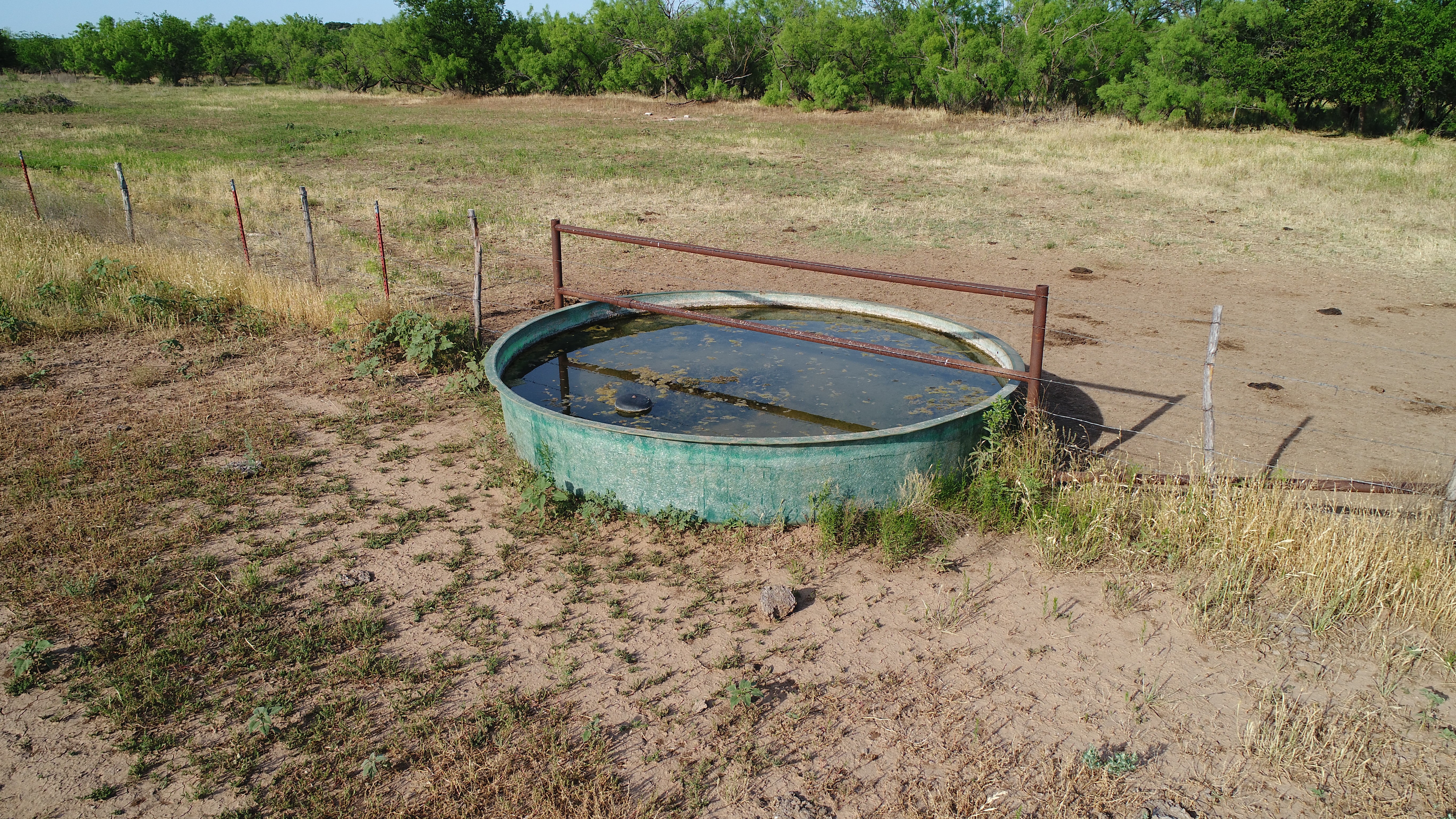 Water trough with metal guardrail sits in a dry pasture, 2,746 acres in Foard County, TX