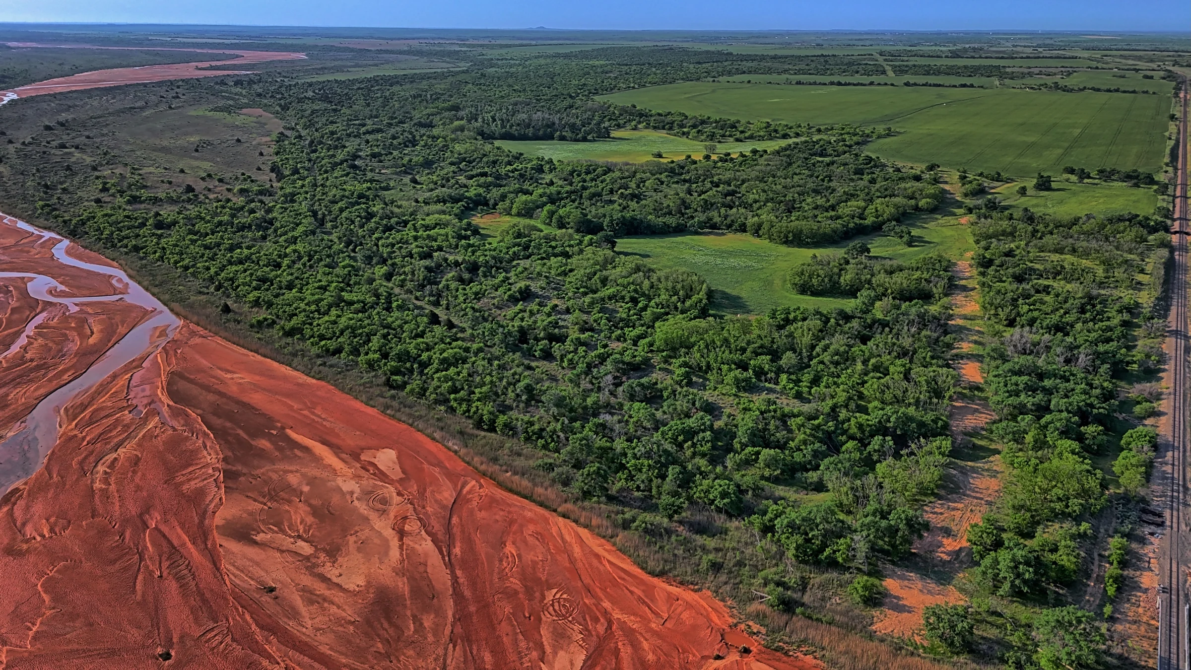Aerial view of Texas ranch terrain beside a red riverbed