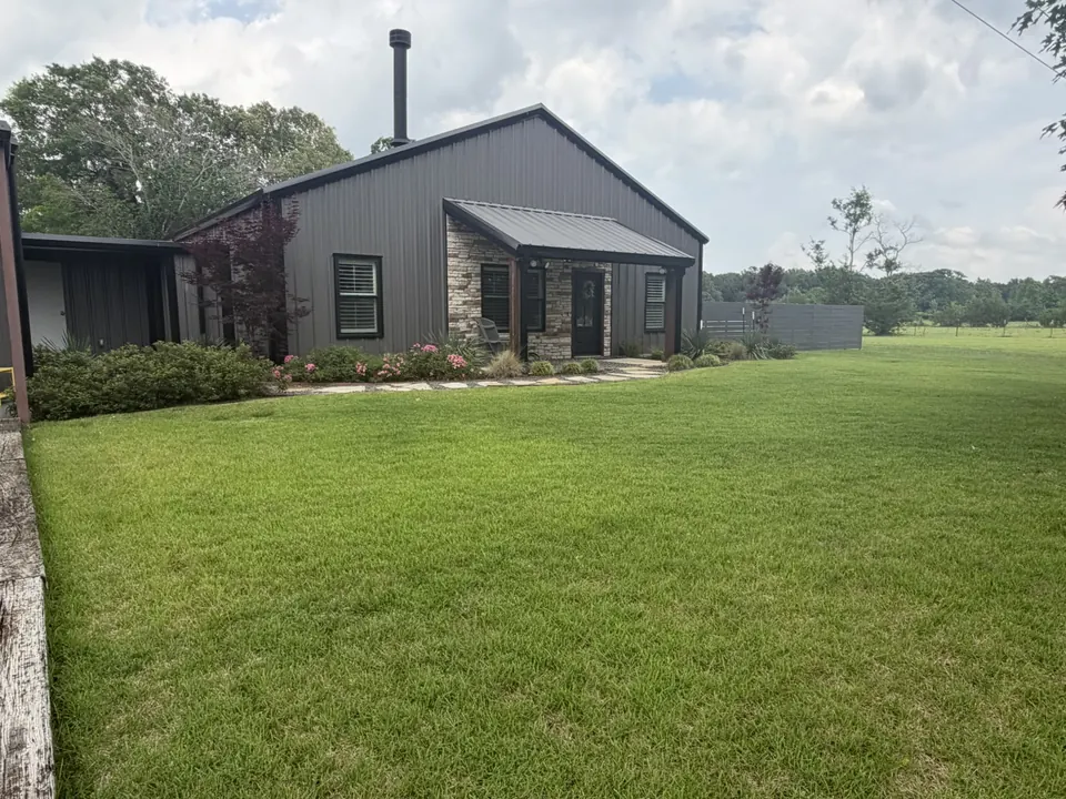 Metal and stone house with a green lawn in Titus County, Texas